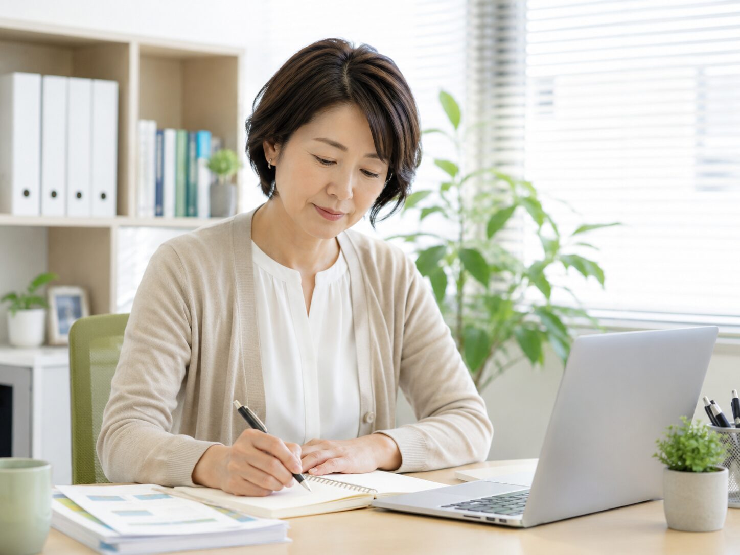 会社のデスクで今の状態をノートに整理する働く女性